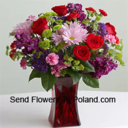 Punaisia ruusuja, vaaleanpunaisia neilikoita ja muita erilaisia kausikukkia lasimaljakossa