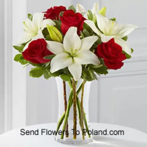Rosas vermelhas e lírios brancos com alguns enchimentos sazonais em um vaso de vidro
